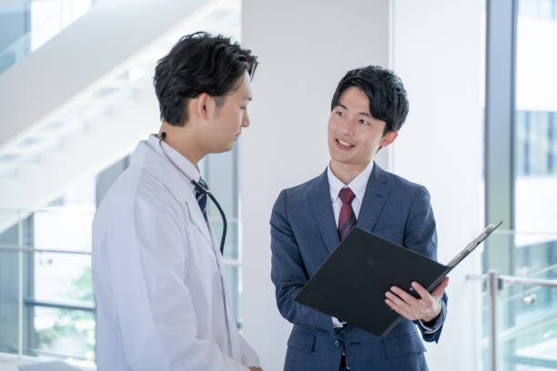 a male doctor and a medical information representative mr talk with smiles at the hospital. - クリニック ストックフォトと画像