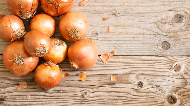 istock Yellow onions on a wooden table. 2179995728