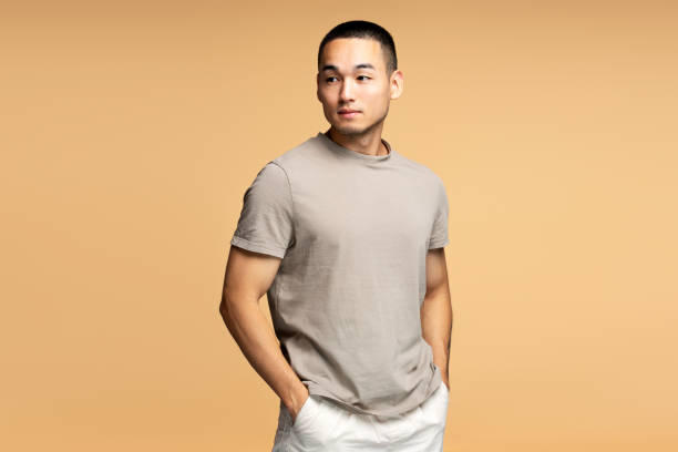 Handsome young man posing with hands in pockets looking away