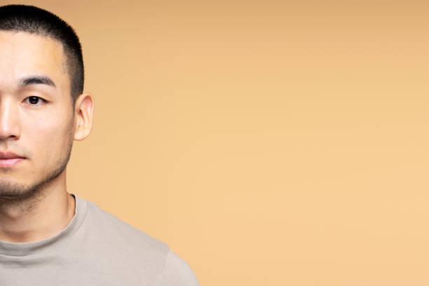 istock Serious young asian man looking at camera on yellow background with copy space 2179999896