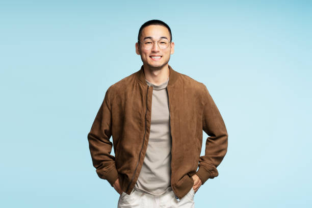 Young man wearing glasses is smiling with hands in pockets