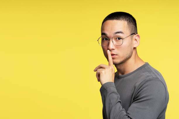 istock Young man with glasses making silence gesture on yellow background 2180000308