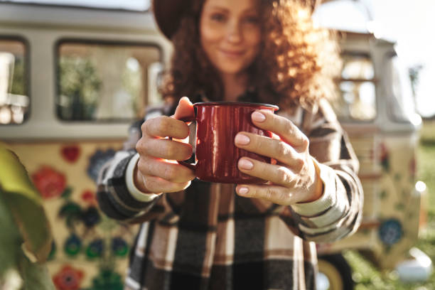 istock Woman Offering a Hot Drink in Front of Camper Van 2180001672