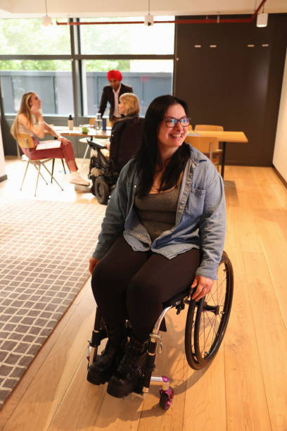 istock Woman on wheelchair moving through office 2180006281