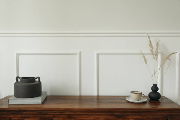 istock Elegant minimal interior still life. Scandinavian interior design. Black boho organic vases with dry flowers grass. Cup of tea, coffee. Empty white wall background. Modern living room design trend. 2180007165