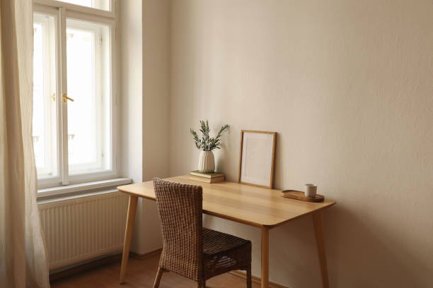 istock Empty vertical picture frame mockup. Wooden desk, table. Vase with olive branches, books, cup of coffee. Elegant working space, home office. Summer interior design. Beige walls. Blurred curtain window 2180007172