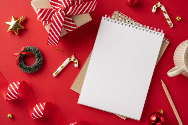 istock Top view of a notepad surrounded by Christmas decorations and gift wrapping on a vibrant red background 2180007487