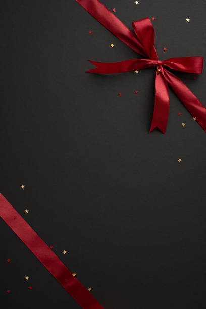 istock A sophisticated vertical image featuring a luxurious red ribbon tied into a bow with scattered star confetti on a dark backdrop, perfect for festive or celebratory themes 2180007524