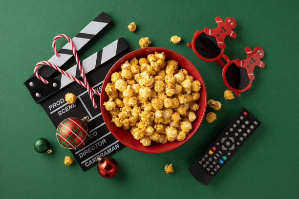 istock A vibrant scene featuring popcorn in a red bowl, surrounded by Christmas ornaments, candy canes, and a film clapperboard, creating a cozy atmosphere for a festive movie night 2180007601
