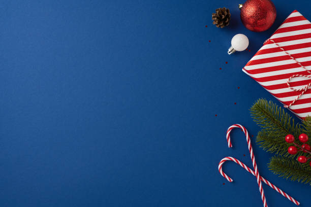 istock Christmas flat lay featuring candy canes, a wrapped gift, pine branches, and ornaments on a blue background 2180007646