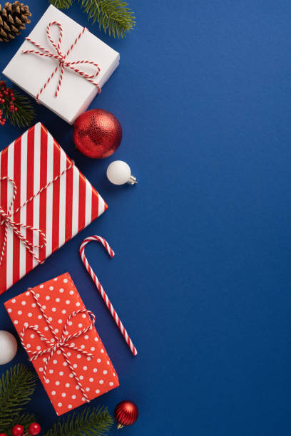 istock Colorful vertical Christmas presents, candy canes, and ornaments arranged on a vibrant blue background evoke festive cheer and celebration 2180007680