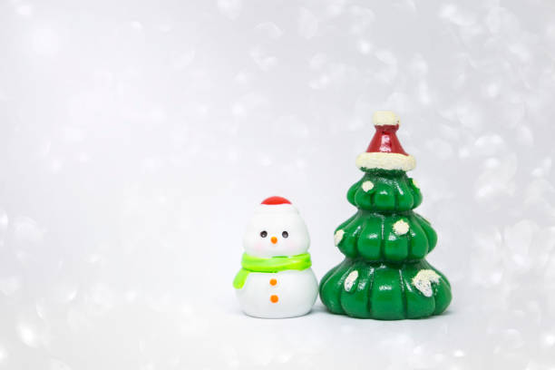 Cute little snow man with Christmas tree over blurred white bokeh background, Christmas card background idea