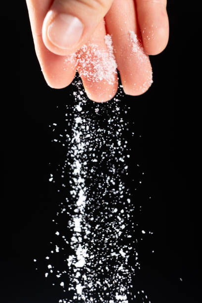 istock Hand pouring white stone salt finely ground, black background. 2180012784