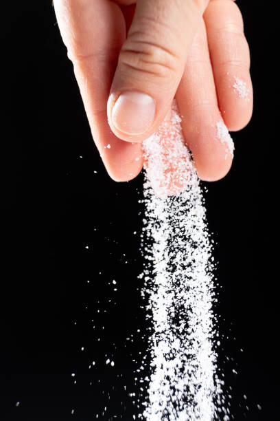 istock Hand pouring white stone salt finely ground, black background. 2180012785