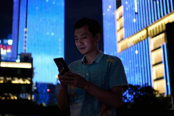 A young Asian man using a smartphone on a blue background
