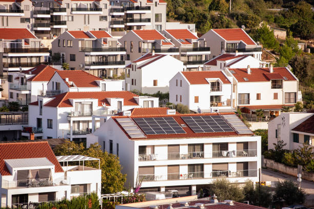 Cluster of modern residential buildings featuring red-tiled roofs, some equipped with solar panels. Represents sustainable living in urban housing with eco-friendly energy solutions. Croatia