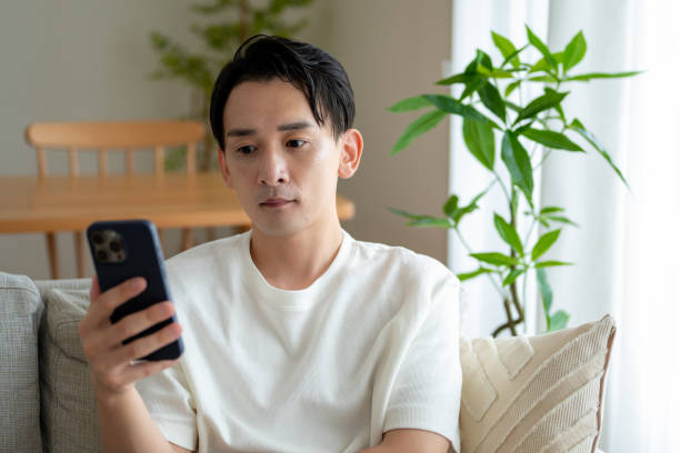 istock A man sitting on a sofa looking at a smartphone 2180039629