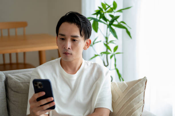 istock A man sitting on a sofa looking at a smartphone 2180044362