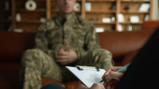 istock Unknown psychologist taking notes writing pen clipboard listen Caucasian male officer camouflage uniform man guy military army soldier veteran explaining trauma war stress psychotherapy indoors office 2180047302