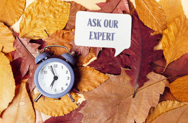 istock Ask our expert text on autumn leaves background with a clock 2180049803