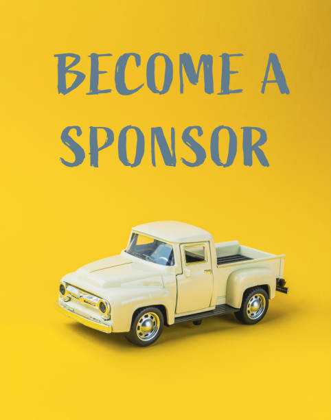 istock Yellow toy truck with become a sponsor text on yellow background 2180050120