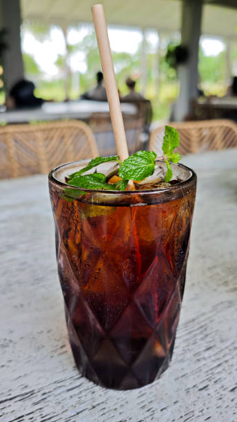 istock Refreshing iced black tea with mint garnish in a textured glass featuring a paper straw on a rustic outdoor cafe table setting for a relaxing beverage break 2180053079