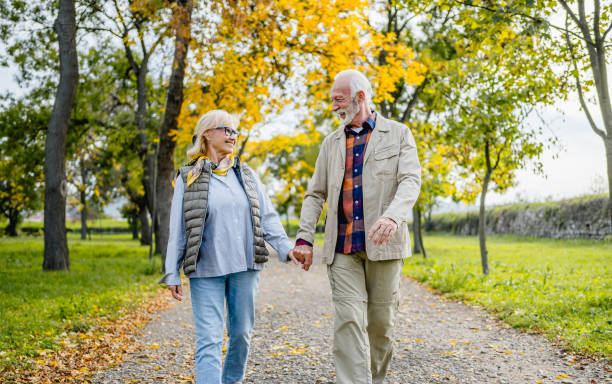 istock Senior couple walking hand in hand through the park 2180055447