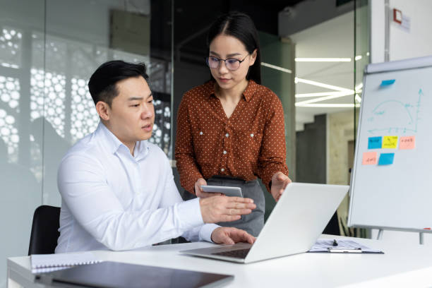 istock Asian business team collaborating on a project with laptop and phone in modern office setup 2180057393