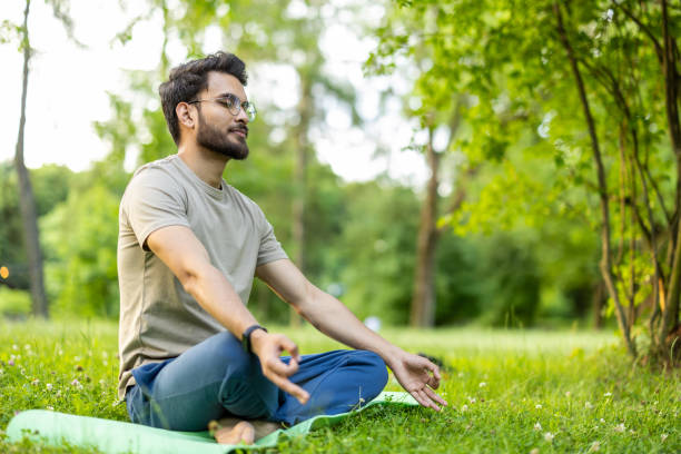 istock Man practicing meditation in a serene park setting surrounded by lush greenery and peaceful nature 2180058109