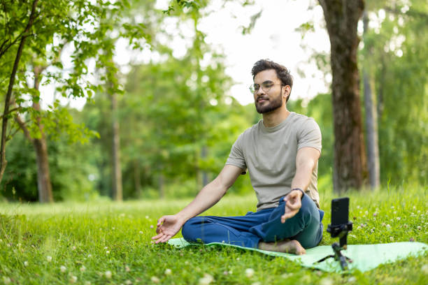 istock Young man meditating in park with smartphone capturing his practice on a sunny day for relaxation and mindfulness 2180059217
