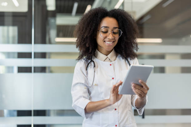 istock Smiling doctor in white coat using tablet in modern office environment for professional communication 2180062060
