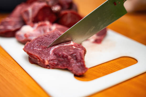 sharp knife plunges into a raw beef steak, symbolizing the artistry of culinary preparation and transformation of ingredients into a delicious meal