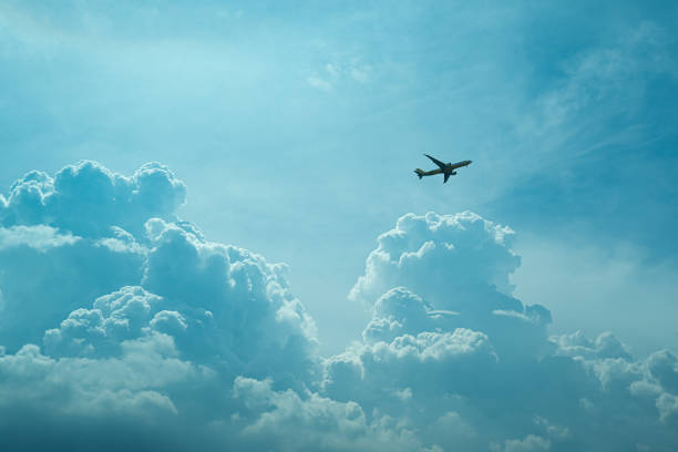 Shadow of an airplane in the sky on a clear day with clouds covering it.