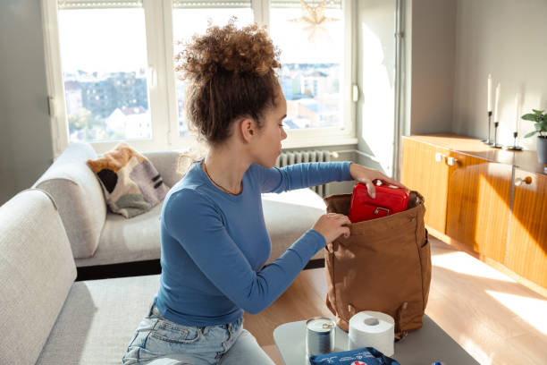 istock Young woman organizing emergency kit in living room setting 2180070250