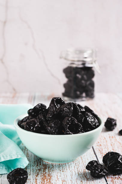 istock Sweet dried prunes in bowl and jar on table vertical view 2180073096