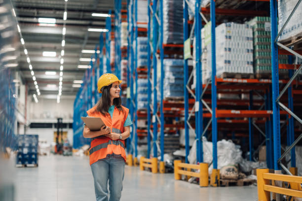 istock Female warehouse worker holding clipboard checking inventory walking through logistics storehouse 2180076632