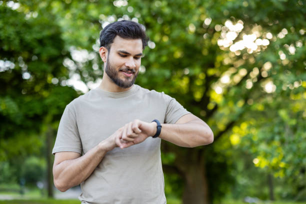 istock Man checking fitness tracker in park during outdoor exercise on a sunny day 2180077251