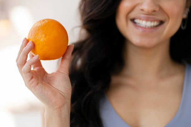 istock Happy brunette woman holding an orange smiling 2180078302