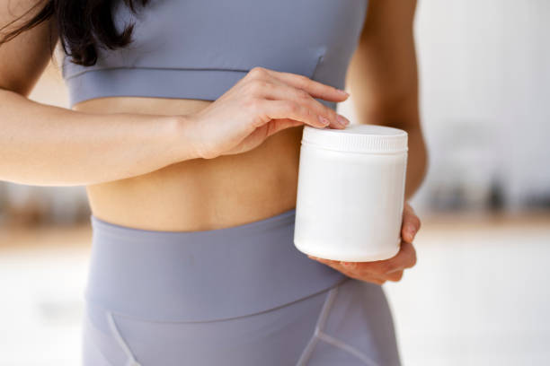 Woman holding white plastic supplement jar after exercising