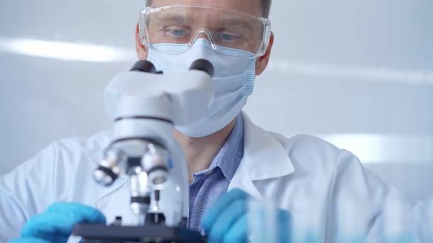 istock Man scientist with protective glasses, mask and gloves is using microscope in laboratory, portrait of researcher. Microbiology science concept 2180079726