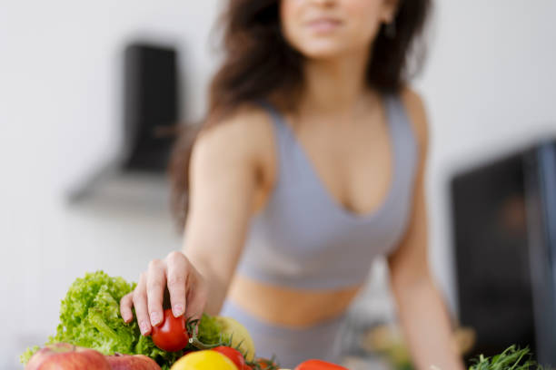 istock Young fit woman choosing cherry tomato from fresh vegetables in kitchen 2180079821