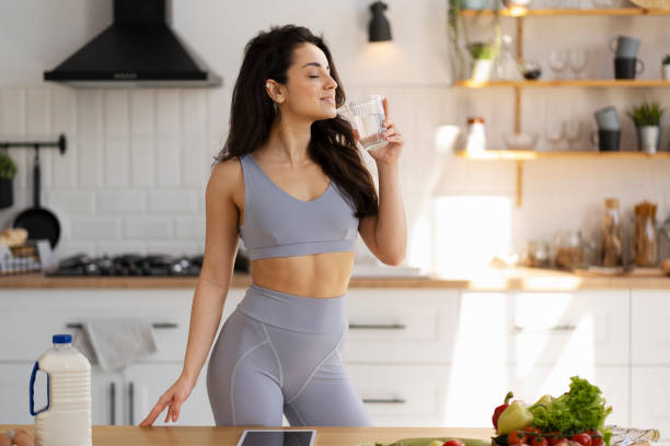 istock Fit woman enjoying a refreshing drink after workout in kitchen 2180080321