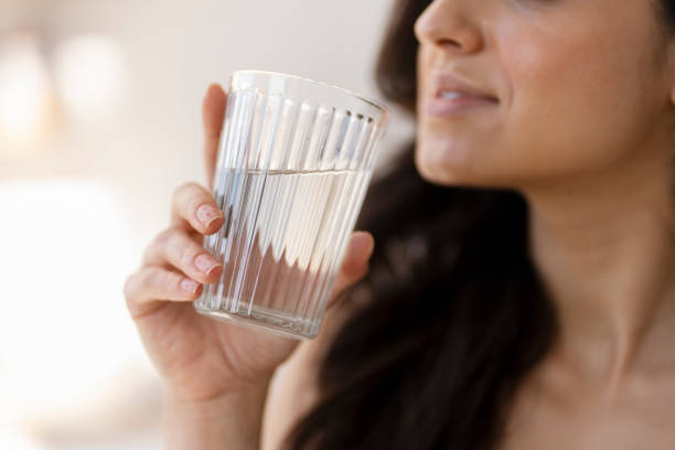 istock Young woman drinking water from a glass 2180080331