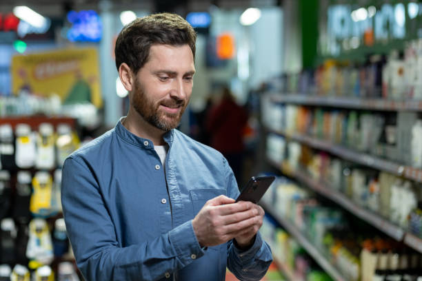 istock Smiling man using smartphone in grocery store aisle checking shopping list or exploring store options 2180083205