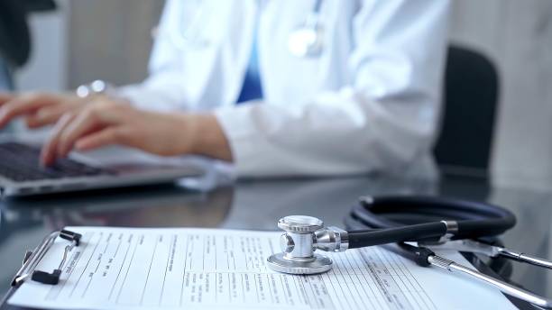 istock Stethoscope and medication record form are on the table besides the working doctor. Workplace in Medicine and Health care 2180083395