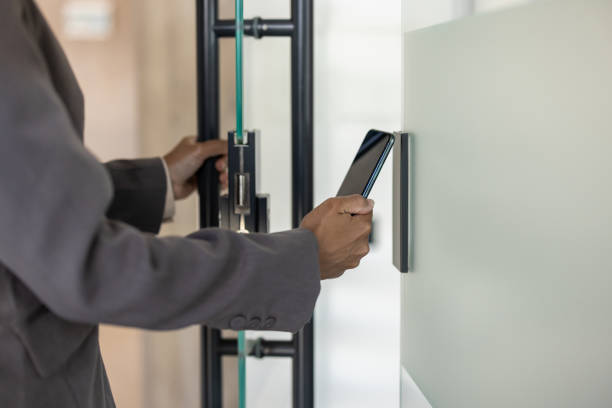 professionista aziendale che utilizza lo smartphone per l'accesso sicuro al moderno edificio per uffici - accessibilità foto e immagini stock