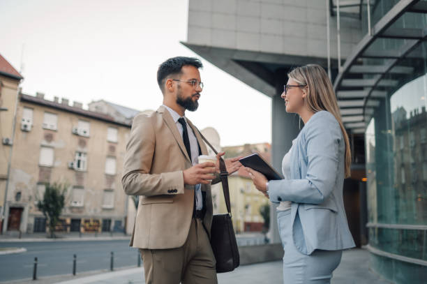 istock Two businesspeople having a discussion while holding a coffee and a tablet in a downtown business district 2180092744