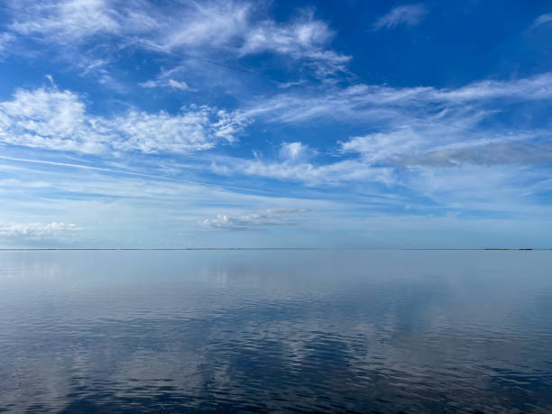 istock Cloudy blue sky over a body of water meets at horizon 2180096409
