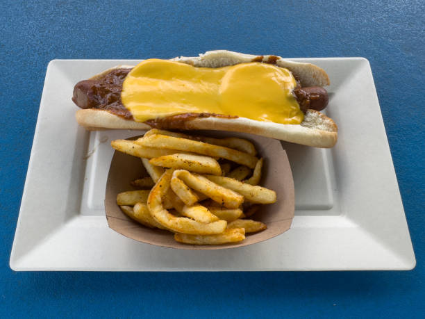 This is a photograph of three hot dogs on a white plate on a white wooden picnic bench. This is a great image for a Fourth of July picnic with a baseball and bat