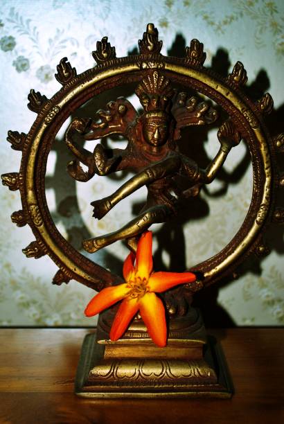 Brass figurine statue of Dancing God Shiva Nataraja  in a home temple setting with flower offering.